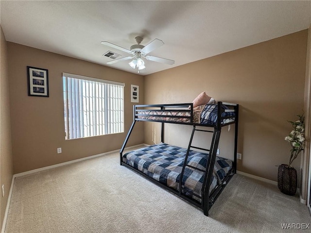 carpeted bedroom featuring a ceiling fan, visible vents, and baseboards