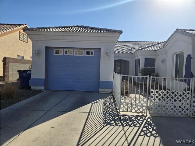 mediterranean / spanish house with driveway, an attached garage, a tiled roof, and stucco siding