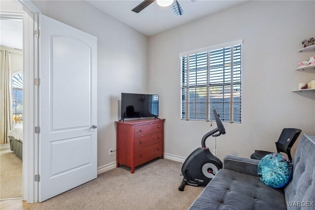 exercise area with light carpet, ceiling fan, and baseboards