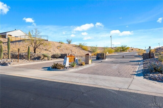 view of street with a gate, a gated entry, and curbs