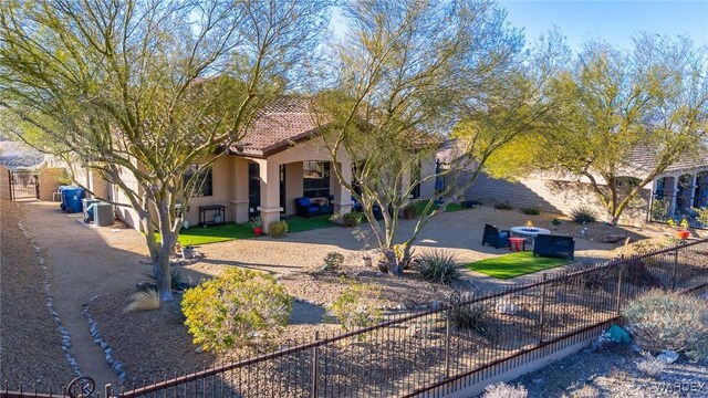 view of front facade with a tiled roof, central AC, fence private yard, and stucco siding