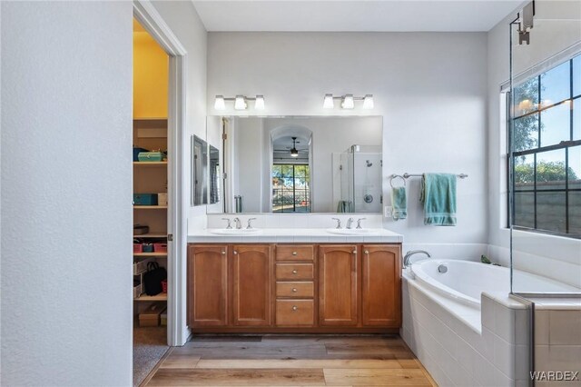 full bath featuring a stall shower, plenty of natural light, a sink, and wood finished floors