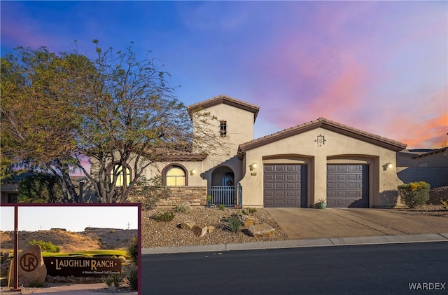 mediterranean / spanish-style home featuring a tile roof, driveway, an attached garage, and stucco siding