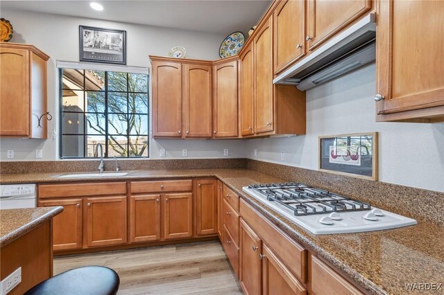 kitchen featuring white appliances, brown cabinetry, and a sink