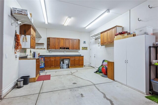 kitchen with light countertops, brown cabinetry, and unfinished concrete flooring