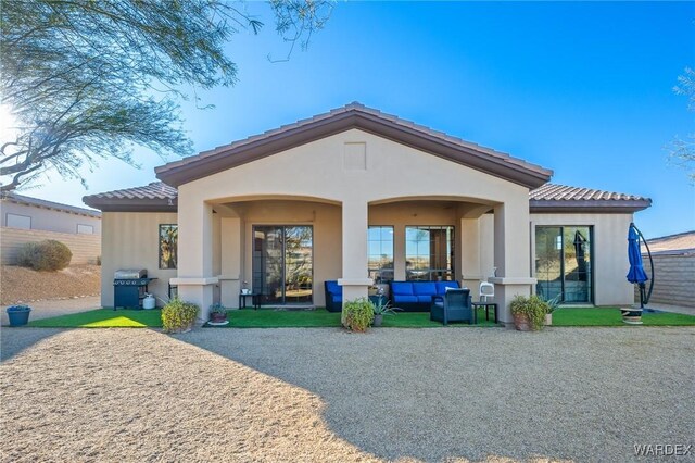 back of house featuring a tiled roof, a patio area, an outdoor hangout area, and stucco siding