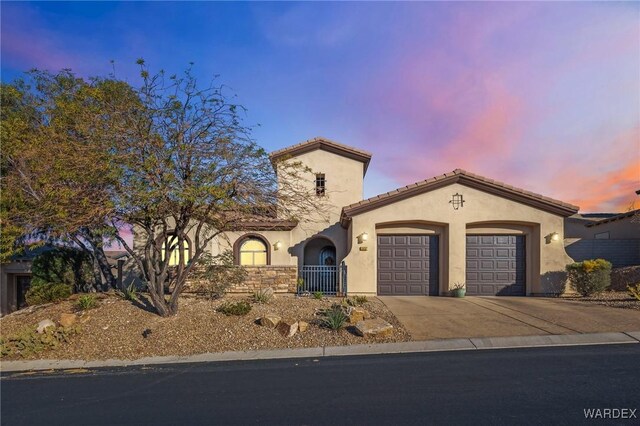 mediterranean / spanish house with a garage, a tile roof, driveway, and stucco siding