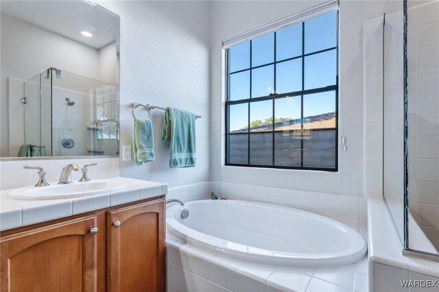 full bath with a garden tub, a shower stall, and vanity