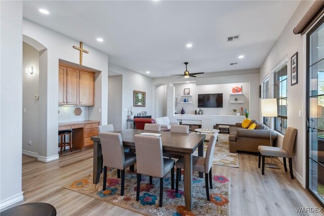 dining area featuring light wood finished floors, visible vents, arched walkways, and recessed lighting