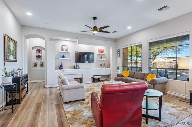 living area featuring light wood-style flooring, visible vents, built in features, and recessed lighting