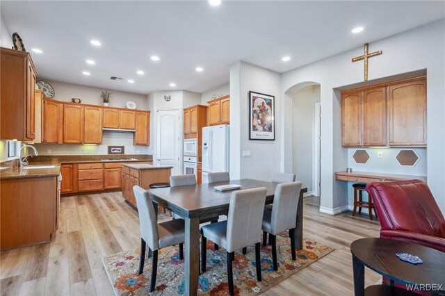 interior space featuring arched walkways, light wood-style flooring, baseboards, and recessed lighting