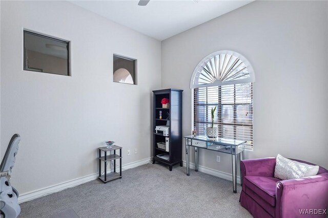 sitting room featuring light carpet, a ceiling fan, and baseboards