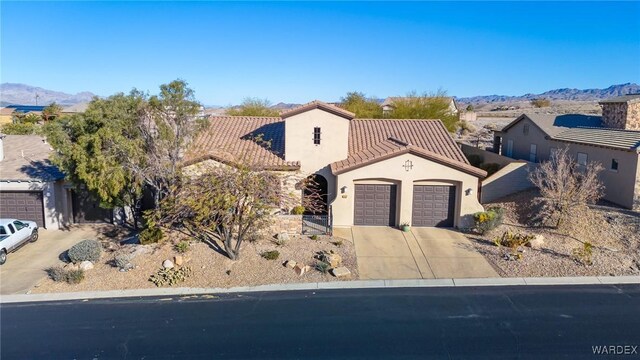 mediterranean / spanish-style house featuring a mountain view, a garage, a tiled roof, concrete driveway, and stucco siding