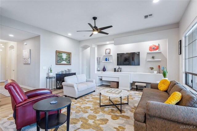 living room with visible vents, arched walkways, ceiling fan, light wood-style floors, and recessed lighting