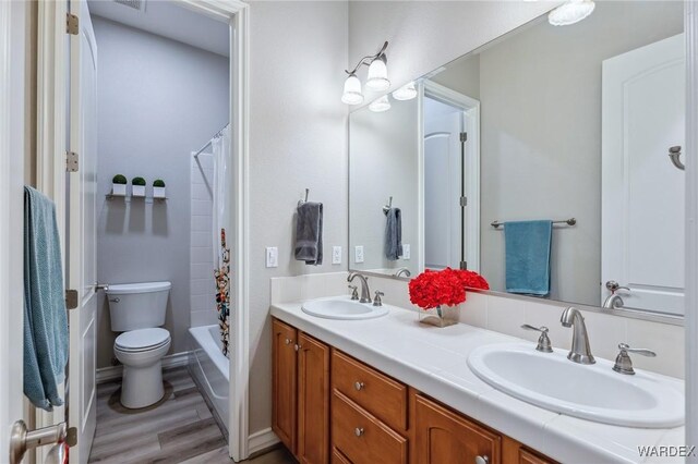 bathroom with wood finished floors, curtained shower, a sink, and toilet