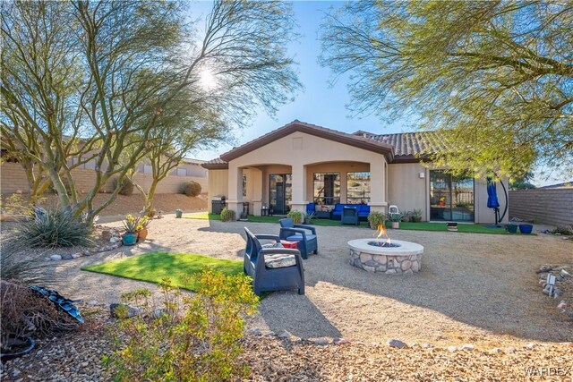 back of property featuring a fenced backyard, a tiled roof, stucco siding, a patio area, and an outdoor living space with a fire pit