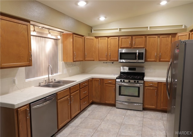 kitchen featuring lofted ceiling, light countertops, decorative backsplash, appliances with stainless steel finishes, and a sink