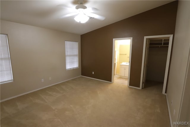 unfurnished bedroom featuring lofted ceiling, a closet, light carpet, and connected bathroom