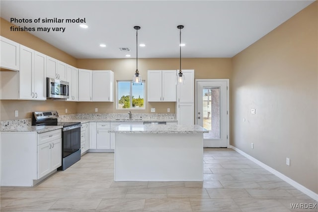 kitchen featuring hanging light fixtures, white cabinetry, stainless steel appliances, and a sink