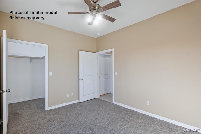 unfurnished bedroom featuring a closet, light colored carpet, a spacious closet, a ceiling fan, and baseboards