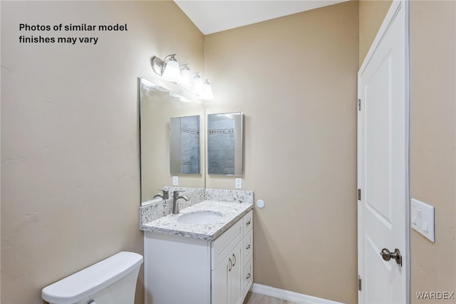 half bath with vanity, toilet, and baseboards