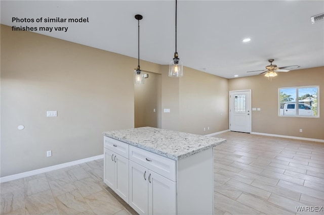 kitchen featuring decorative light fixtures, open floor plan, white cabinetry, light stone countertops, and baseboards