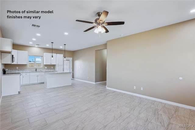 kitchen with a kitchen island, visible vents, white cabinetry, open floor plan, and decorative light fixtures