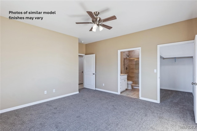 unfurnished bedroom featuring ensuite bath, a spacious closet, baseboards, and light colored carpet