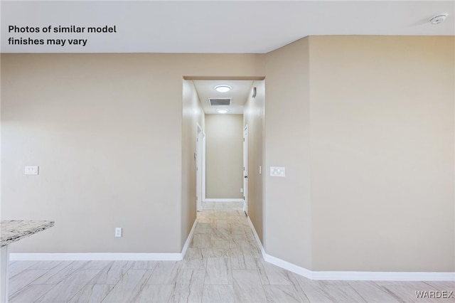 hallway featuring baseboards and visible vents