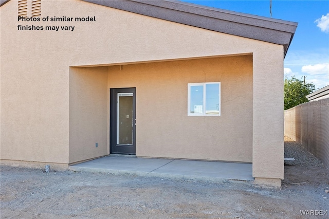 rear view of house featuring a patio area, fence, and stucco siding