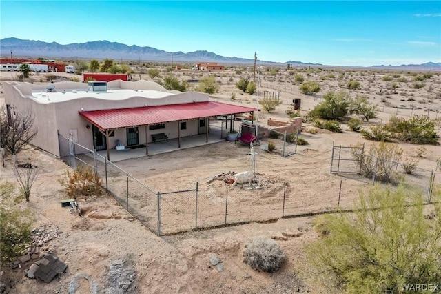 exterior space featuring metal roof, a mountain view, driveway, stucco siding, and an exterior structure