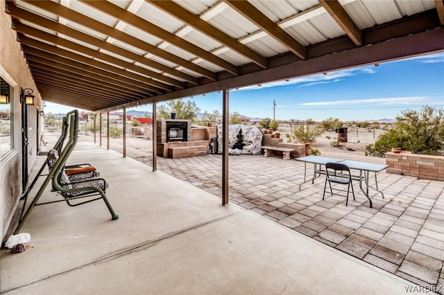 view of patio with outdoor dining space, an outdoor stone fireplace, and fence