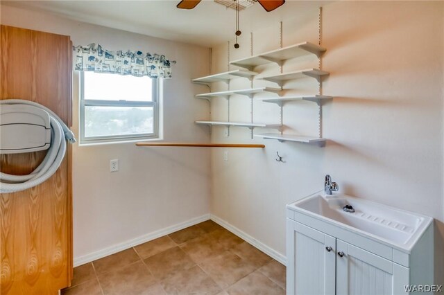 clothes washing area featuring ceiling fan, light tile patterned floors, cabinet space, and baseboards