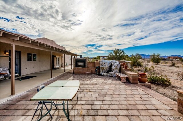 view of patio with exterior fireplace and a mountain view