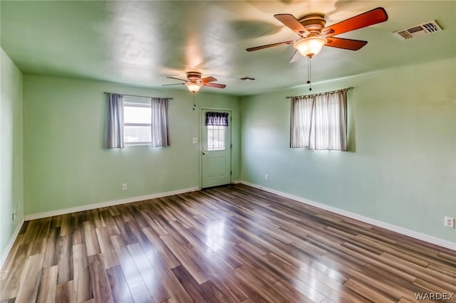 unfurnished room with a ceiling fan, wood finished floors, visible vents, and baseboards