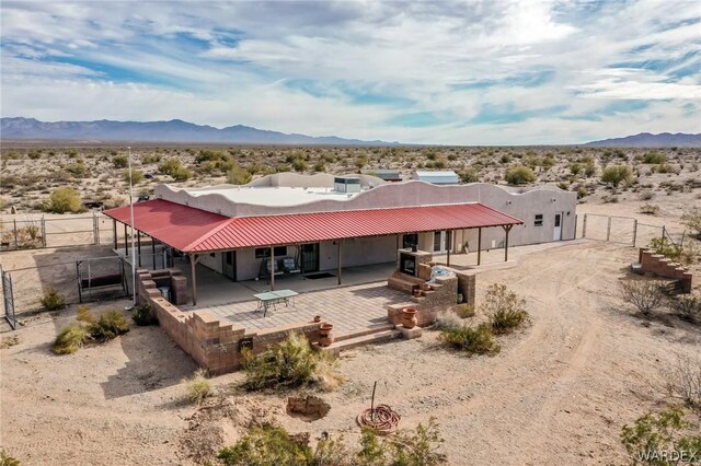 rear view of house featuring an outbuilding, an exterior structure, a mountain view, and dirt driveway