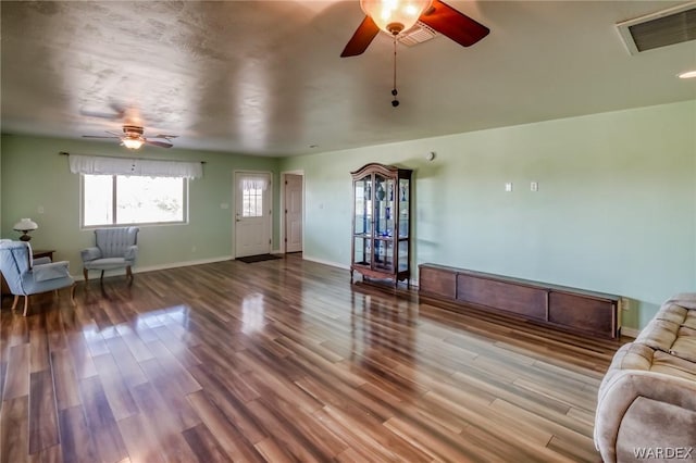 unfurnished living room with visible vents, ceiling fan, baseboards, and wood finished floors