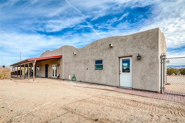 rear view of property with a patio area, fence, and stucco siding