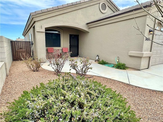 view of front of property with an attached garage, fence, and stucco siding