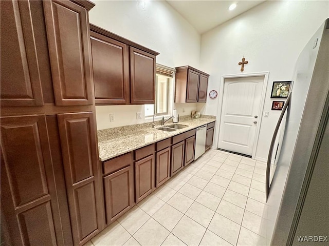 kitchen featuring light tile patterned floors, arched walkways, dishwasher, light stone counters, and a sink