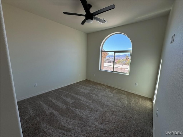 spare room featuring ceiling fan, dark colored carpet, and baseboards