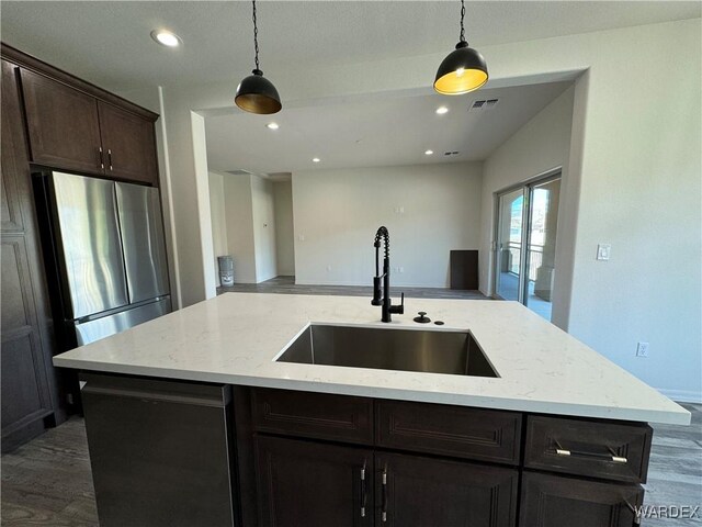 kitchen with a center island with sink, visible vents, freestanding refrigerator, open floor plan, and a sink