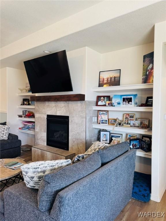 living room with a tiled fireplace and wood finished floors