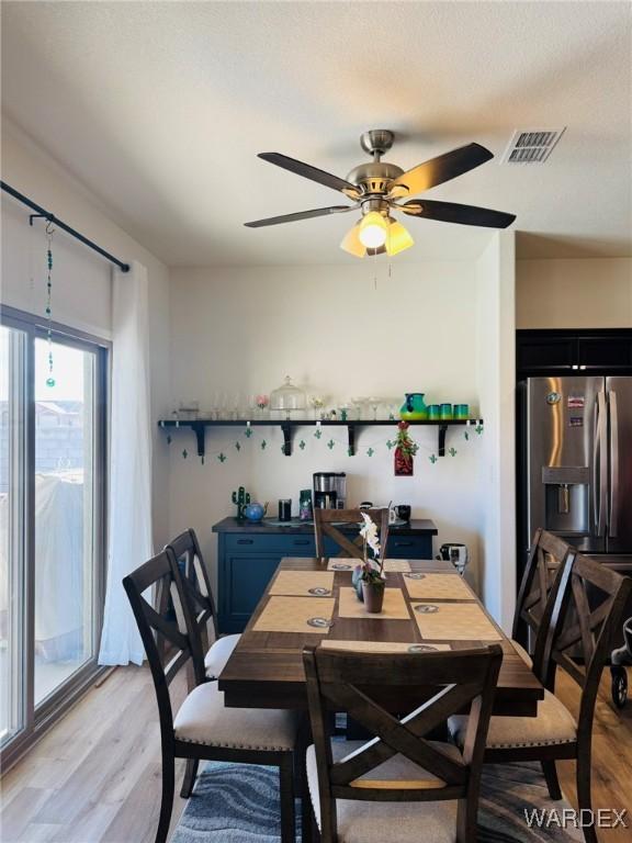 dining room with a ceiling fan, light wood-type flooring, and visible vents