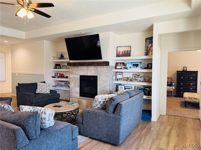 living room featuring ceiling fan, wood finished floors, and a fireplace