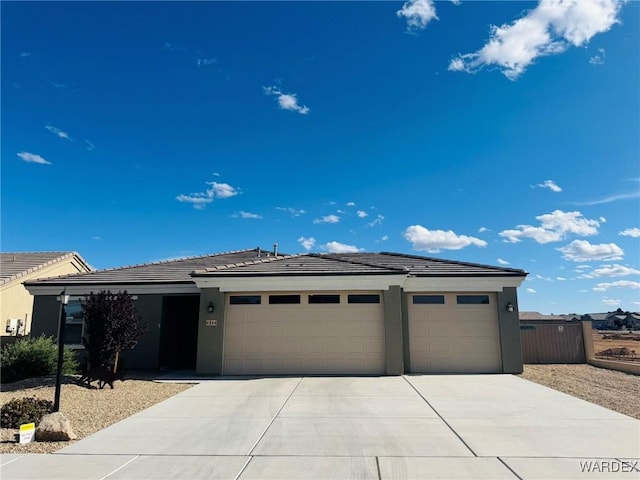 view of front of property featuring a garage, stucco siding, a tile roof, and concrete driveway