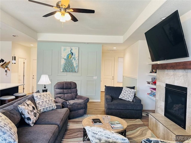 living room featuring a ceiling fan, baseboards, recessed lighting, wood finished floors, and a tile fireplace