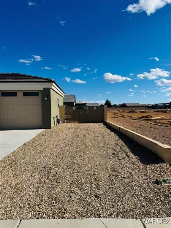 view of home's exterior with an attached garage, stucco siding, fence, and concrete driveway