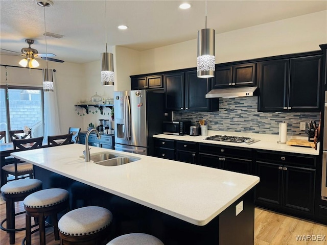 kitchen with dark cabinets, a sink, a breakfast bar area, and stainless steel appliances