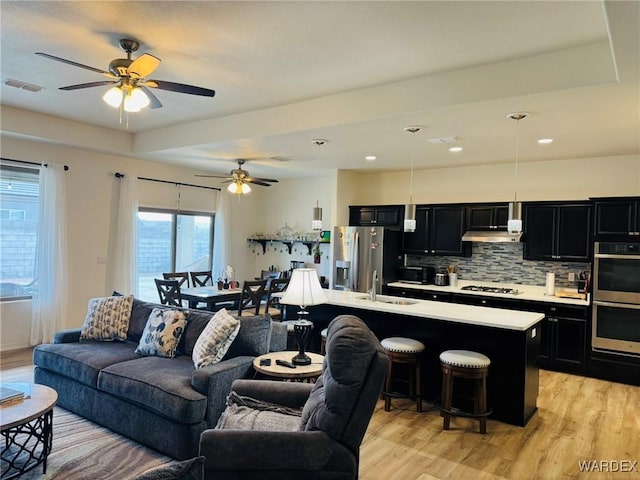 living area featuring a ceiling fan, visible vents, and light wood-type flooring